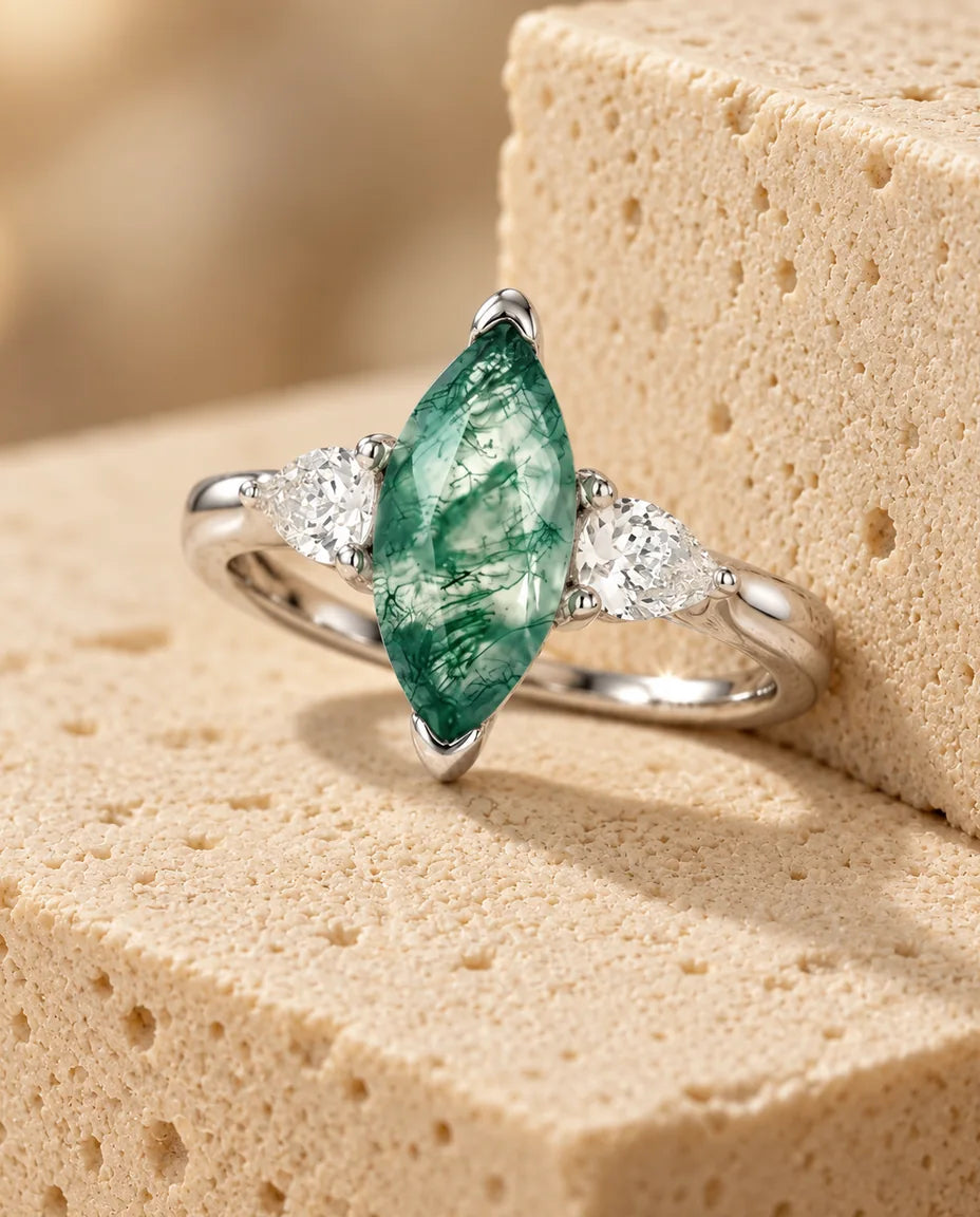 Anillo de ágata musgosa talla marquesa de 5x10 mm - expuesto sobre un bloque de travertino