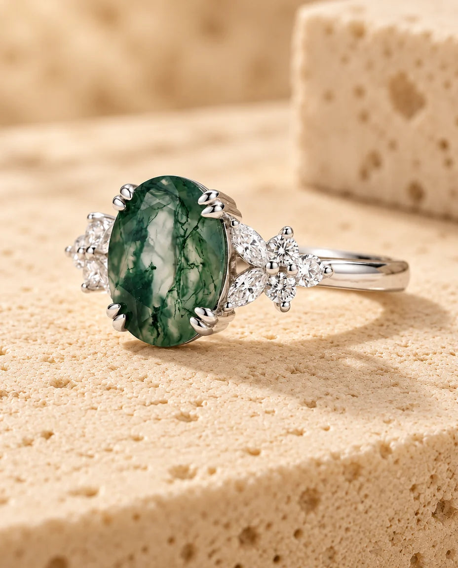 Anillo de ágata musgosa ovalada de 7x9 mm - expuesto sobre un bloque de travertino