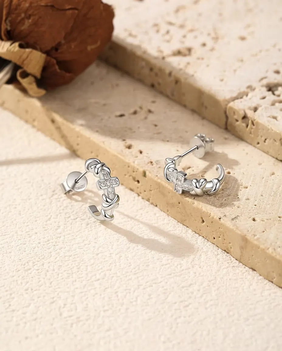 Pendientes de Aro con Cruz de Moissanita en Plata 925 - el par uno junto al otro sobre una superficie clara con textura