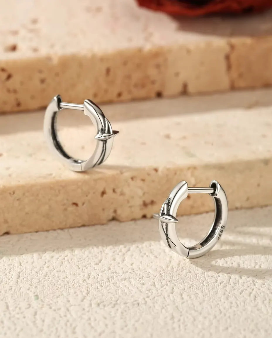 Pendientes Aro Huggie con Estrella en Plata 925 - el par sobre unos escalones de travertino