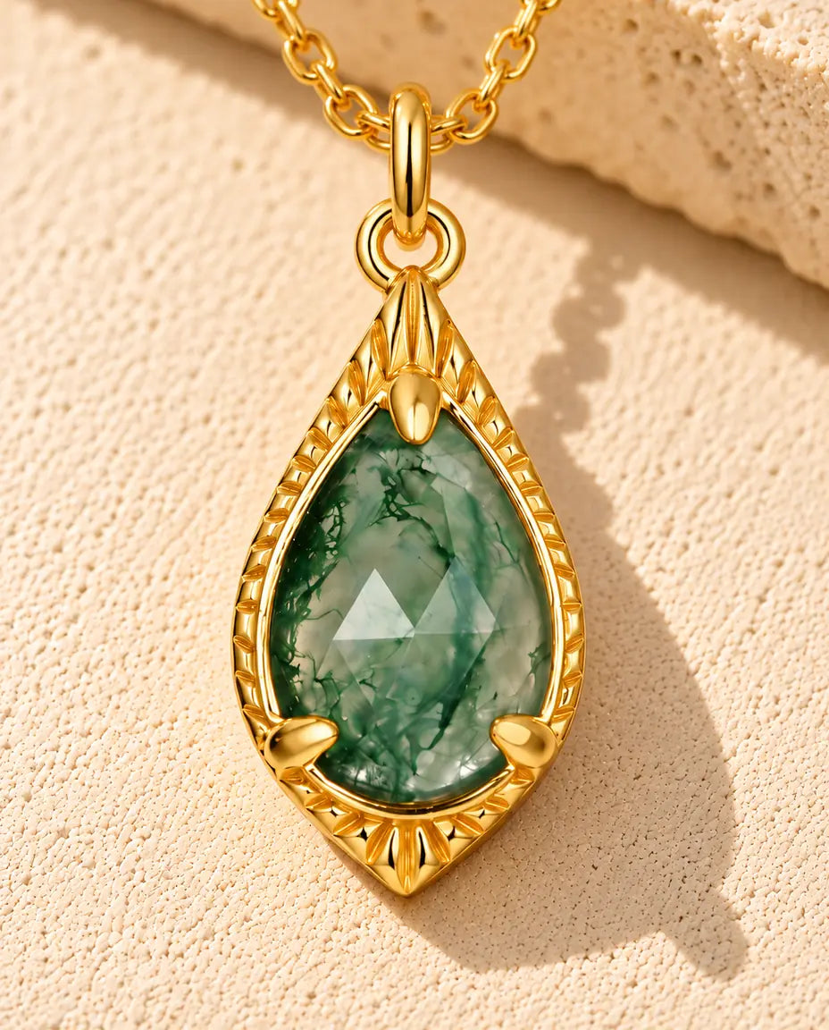 Collar de Ágata Musgosa en Forma de Gota en Plata 925 Chapada en Oro - sobre una superficie clara con textura junto a un bloque de travertino