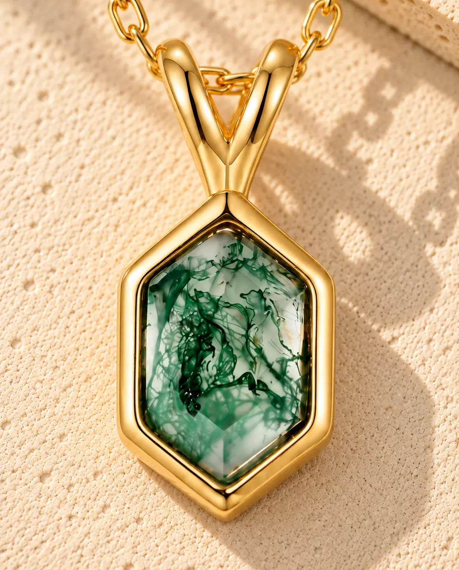 Collar de Ágata Musgosa Hexagonal en Plata 925 Chapada en Oro - sobre una superficie clara con textura junto a un bloque de travertino