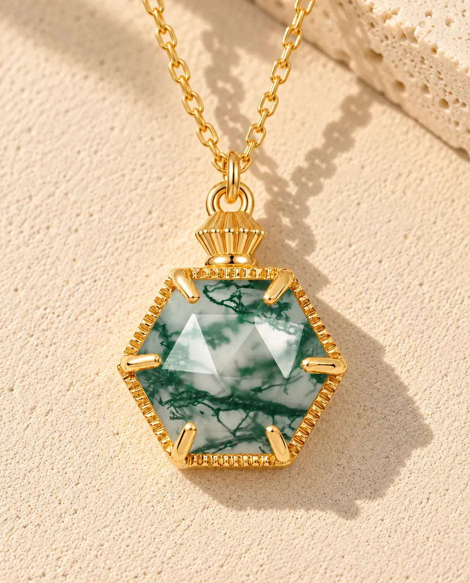 Collar de Ágata Musgosa Hexagonal en Plata 925 Chapada en Oro - sobre una superficie clara con textura junto a un bloque de travertino