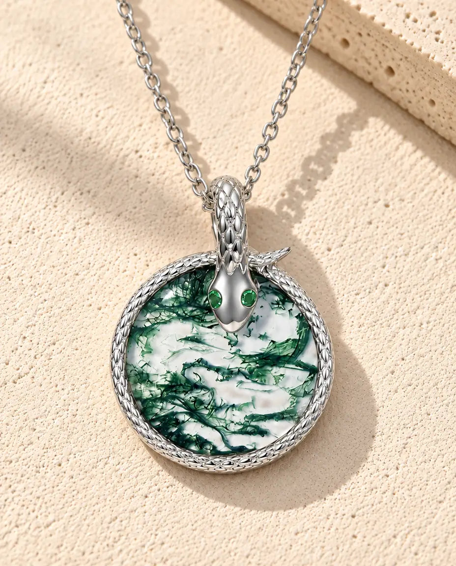 Collar de Ágata Musgosa Serpiente en Plata 925 - sobre una superficie clara con textura junto a un bloque de travertino