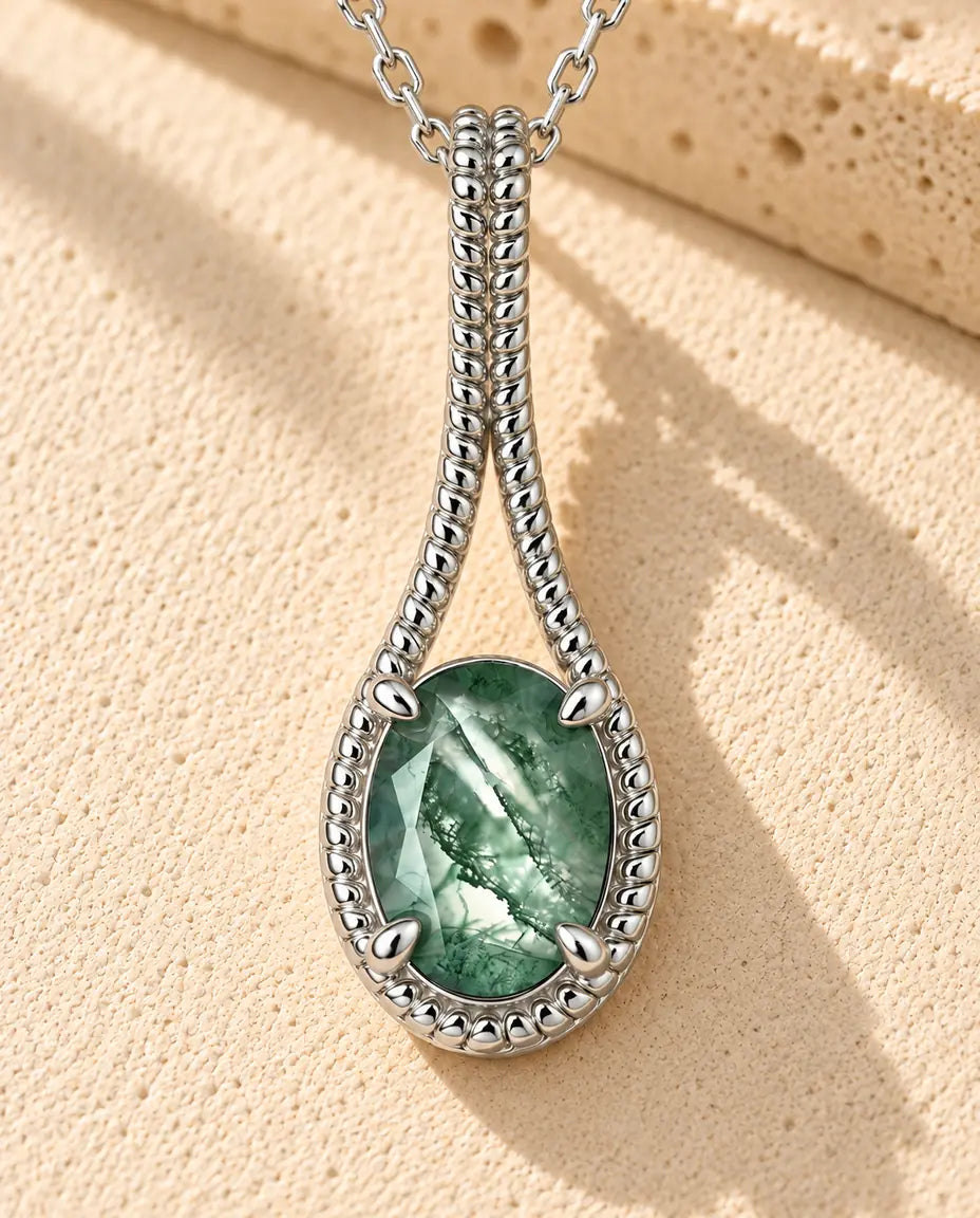 Collar de Ágata Musgosa Ovalada en Plata 925 - sobre una superficie clara con textura junto a un bloque de travertino