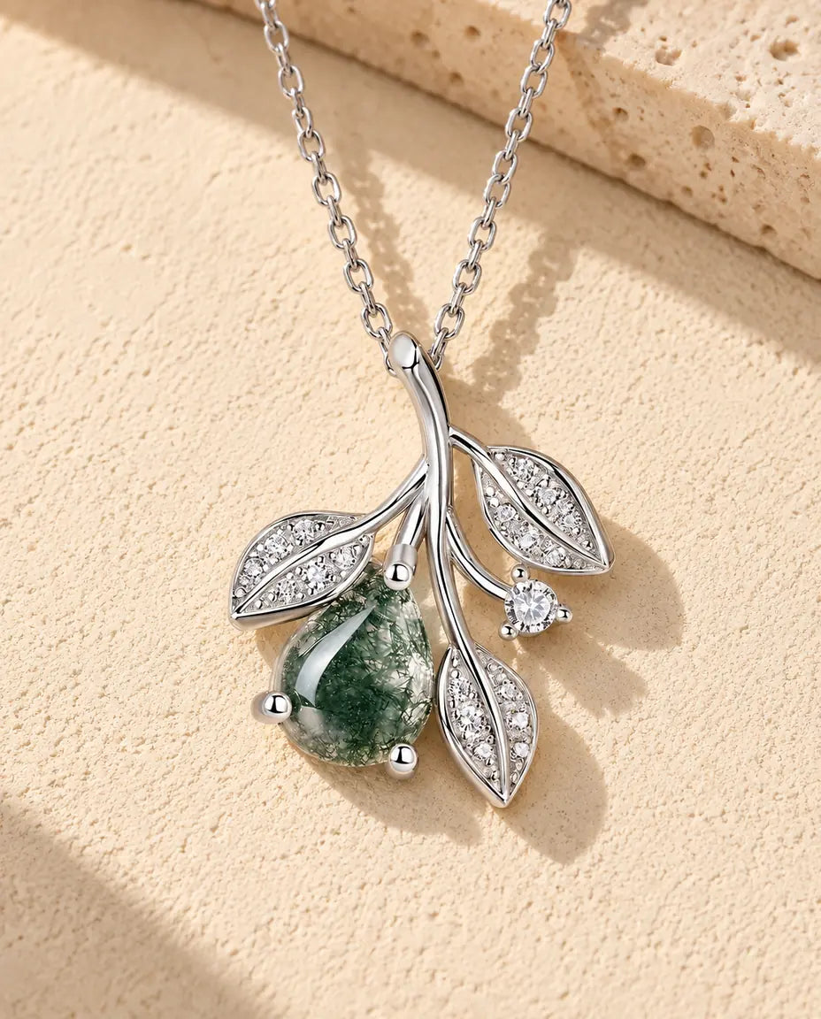 Collar de Ágata Musgosa con Hojas en Plata 925 - sobre una superficie clara con textura junto a un bloque de travertino