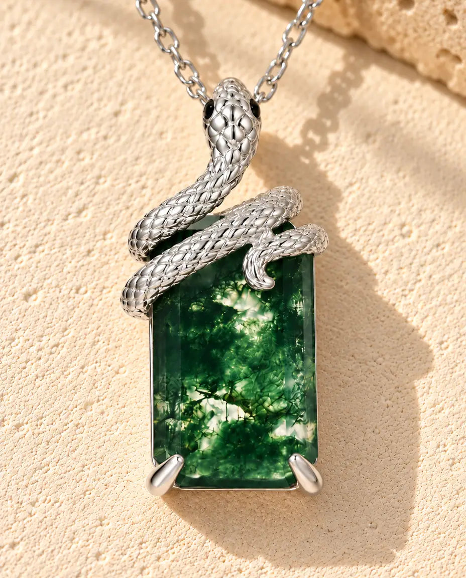 Collar de Ágata Musgosa con Serpiente en Plata 925 - sobre una superficie clara con textura junto a un bloque de travertino