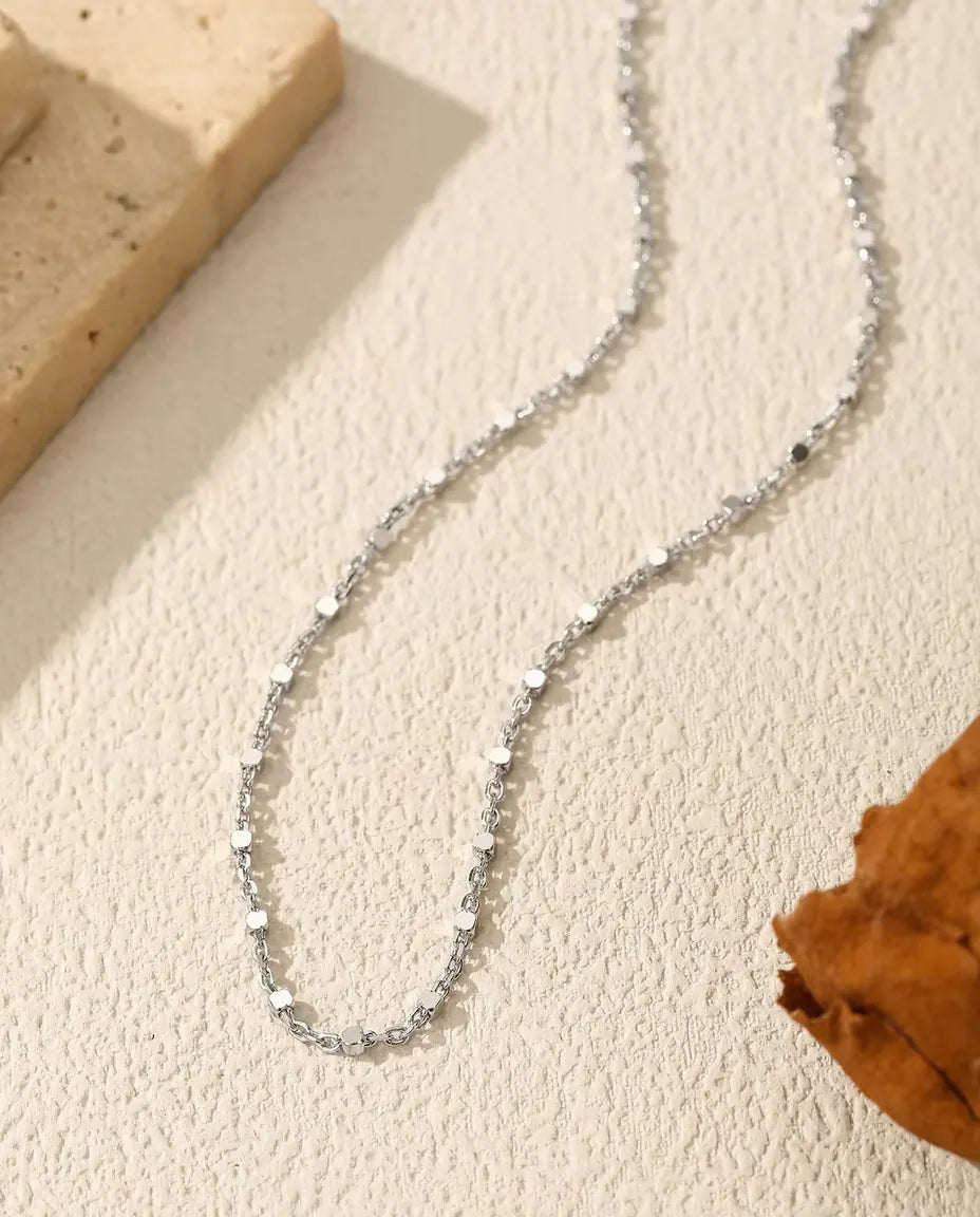 Collar Cadena con Lentejuelas en Plata 925 - sobre una superficie clara junto a una losa de travertino