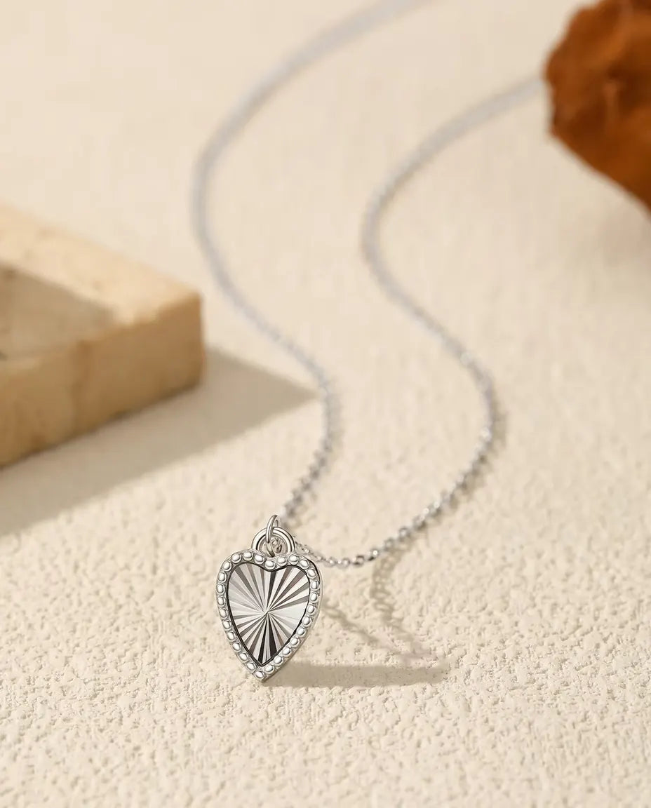 Collar con Colgante de Corazón en Plata 925 - colgante sobre una superficie clara junto a una losa de travertino