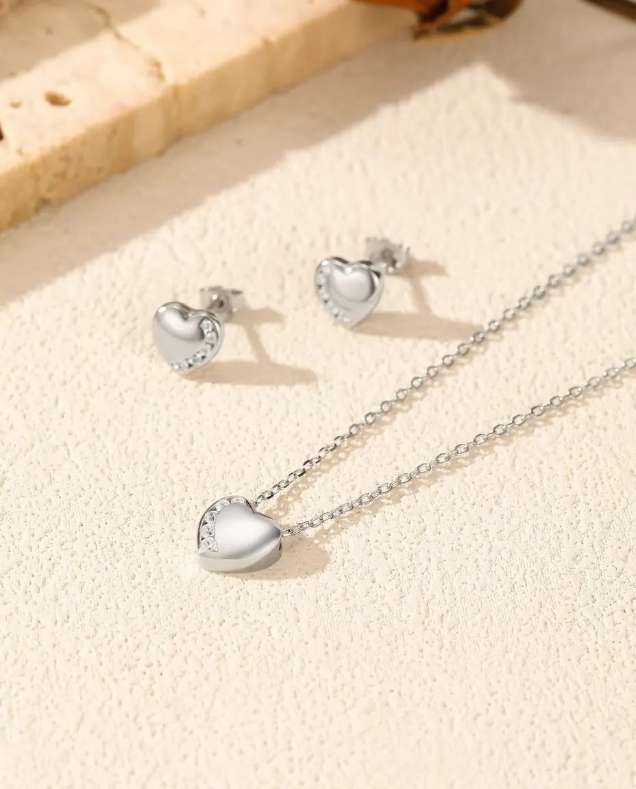 Conjunto Corazón en Plata 925 - collar y pendientes juntos sobre una superficie clara con textura