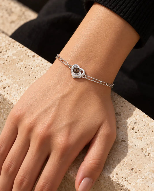 Mujer con la pulsera plateada de doble corazón con foto dentro en la muñeca, bajo una cálida luz de sol