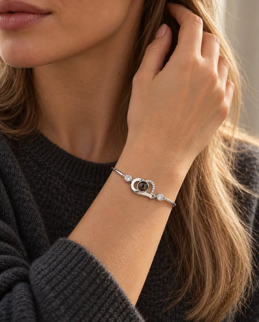 Mujer con la mano en el pelo y la pulsera plateada de corazón abierto con foto dentro
