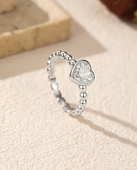Anillo de Corazón con Moissanita en Plata 925 - de pie sobre una superficie clara con textura