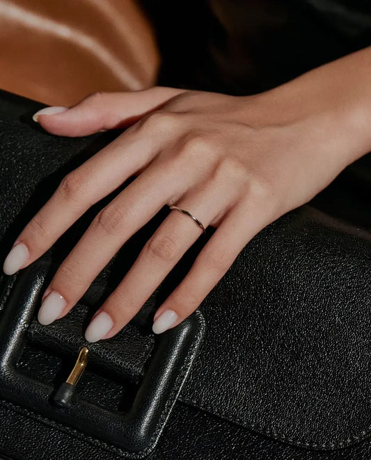 Anillo Ondulado en Plata 925 - llevado en una mano apoyada sobre un bolso negro