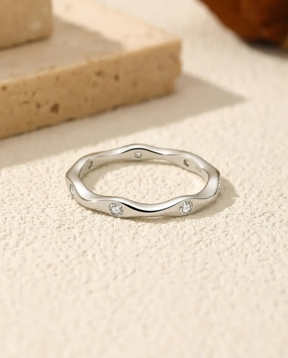 Anillo de Moissanita Ondulado en Plata 925 - tumbado sobre una superficie clara con textura