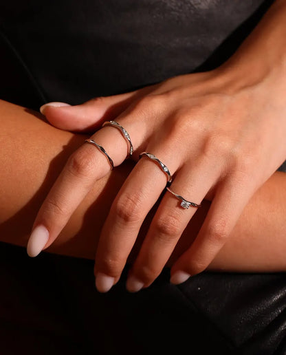 Anillo de Moissanita Ondulado en Plata 925 - llevado junto a otros anillos, primer plano de los dedos