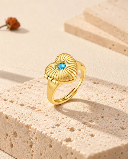 Anillo relicario de corazón cerrado, de pie sobre un bloque de travertino