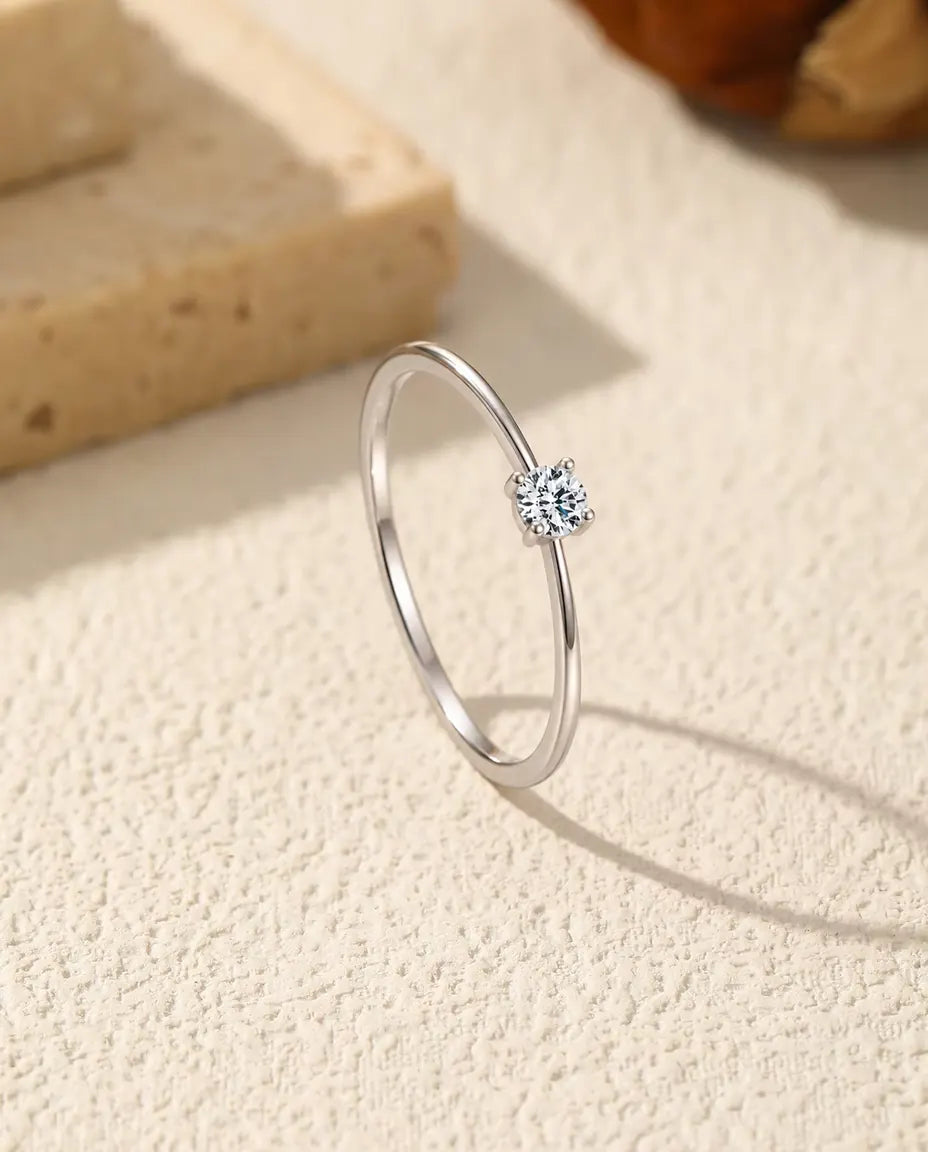 Anillo Solitario de Moissanita Fino en Plata 925 - de pie sobre una superficie clara con textura