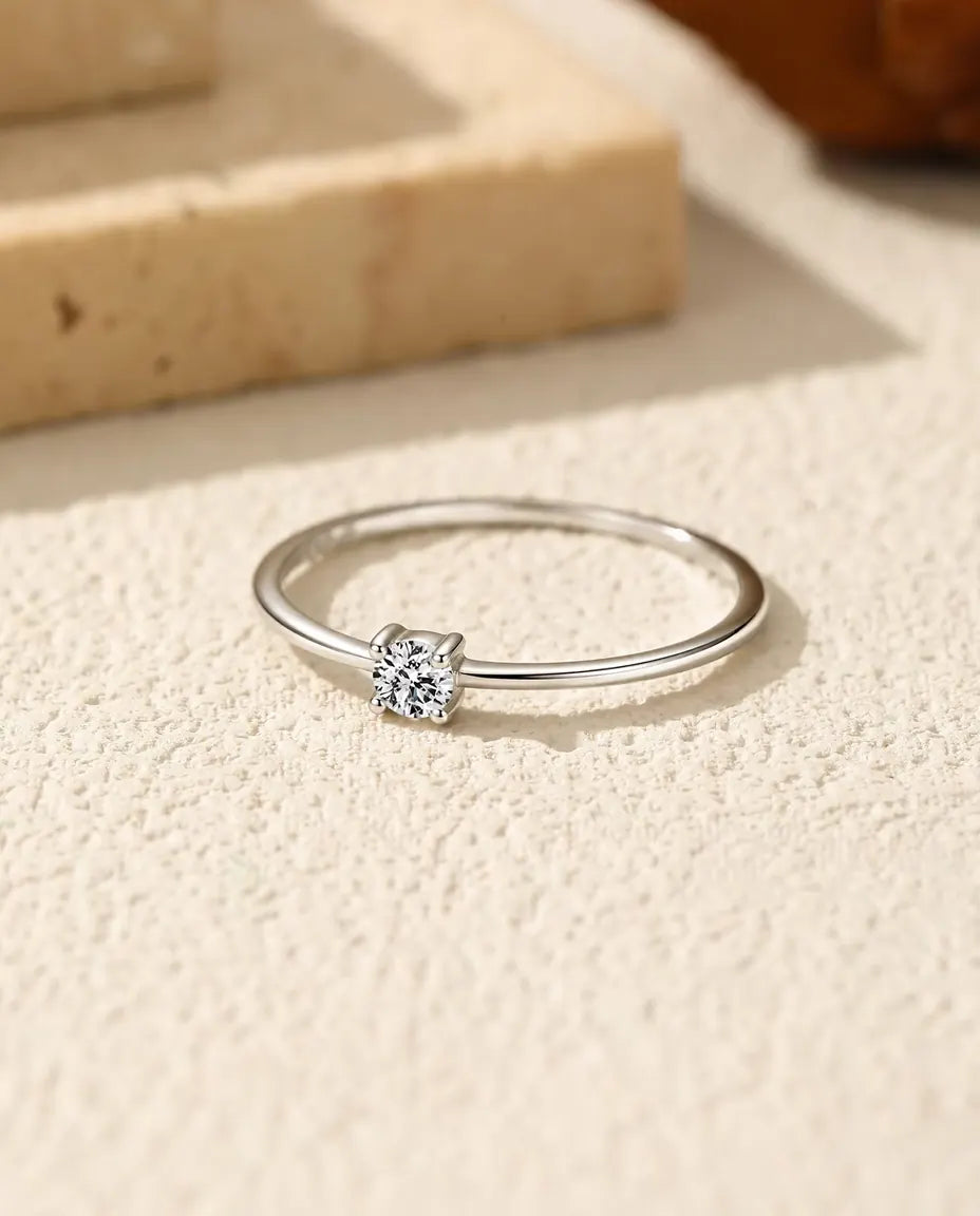 Anillo Solitario de Moissanita Fino en Plata 925 - tumbado sobre una superficie clara con textura