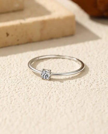 Anillo Solitario de Moissanita Fino en Plata 925 - tumbado sobre una superficie clara con textura