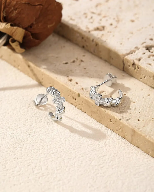 Pendientes de Aro con Cruz de Moissanita en Plata 925 - el par uno junto al otro sobre una superficie clara con textura