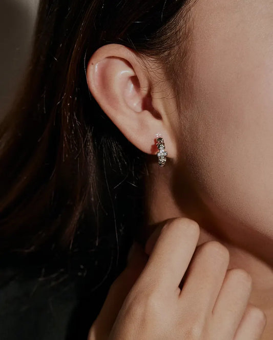 Pendientes de Aro con Cruz de Moissanita en Plata 925 - llevados en la oreja de una modelo, con la mano cerca de la cara
