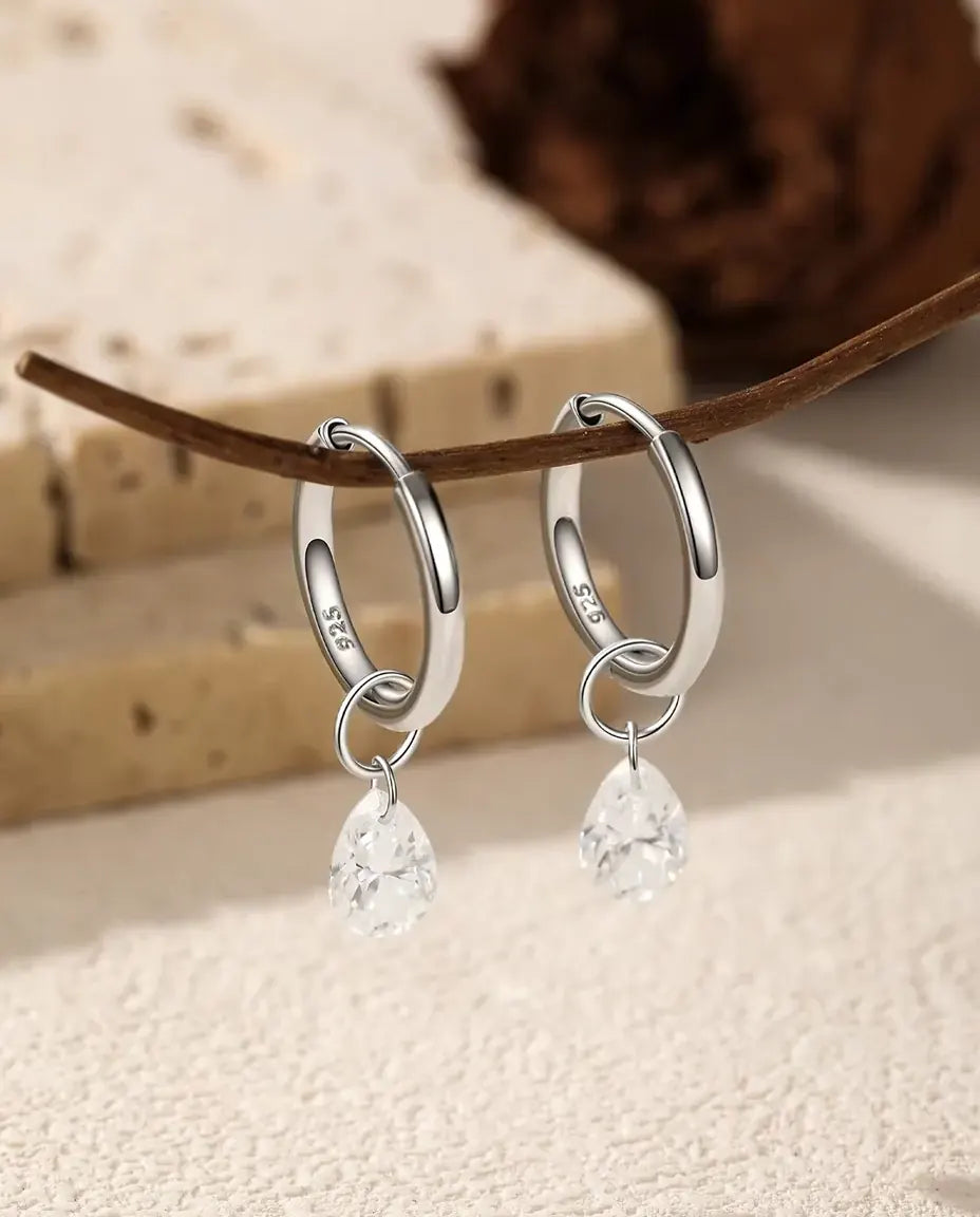 Pendientes de Aro de Moissanita Talla Pera en Plata 925 - el par colgado de una rama fina