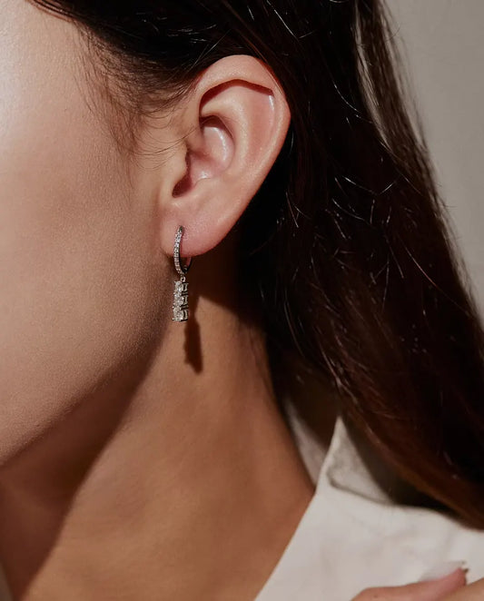 Pendientes de Aro Colgantes con Tres Moissanitas en Plata 925 - llevados en la oreja de una modelo, primer plano