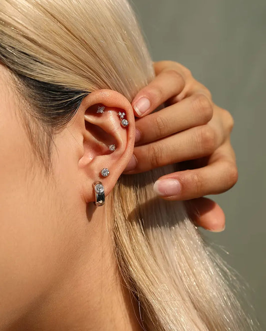 Pendientes Aro Huggie de Moissanita Oval en Plata 925 - llevado por una modelo que se aparta el pelo tras la oreja