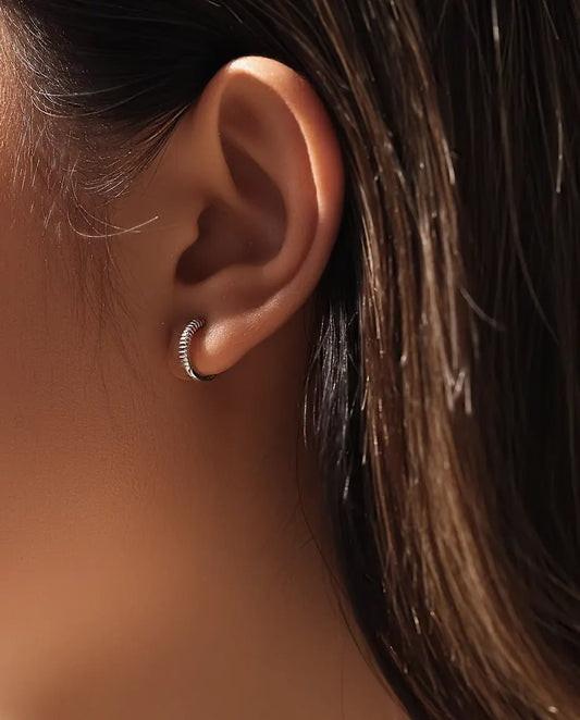 Pendientes Aro Huggie Estriados en Plata 925 - llevados en la oreja de una modelo, primer plano