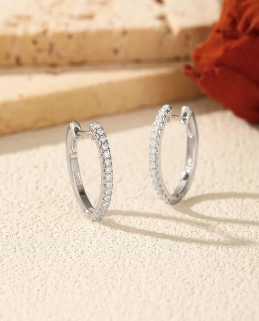 Pendientes de Aro de Moissanita en U en Plata 925 - el par uno junto al otro sobre una superficie clara con textura