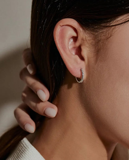 Pendientes de Aro de Moissanita en Plata 925 - llevados en la oreja de una modelo, con la mano apartando el pelo