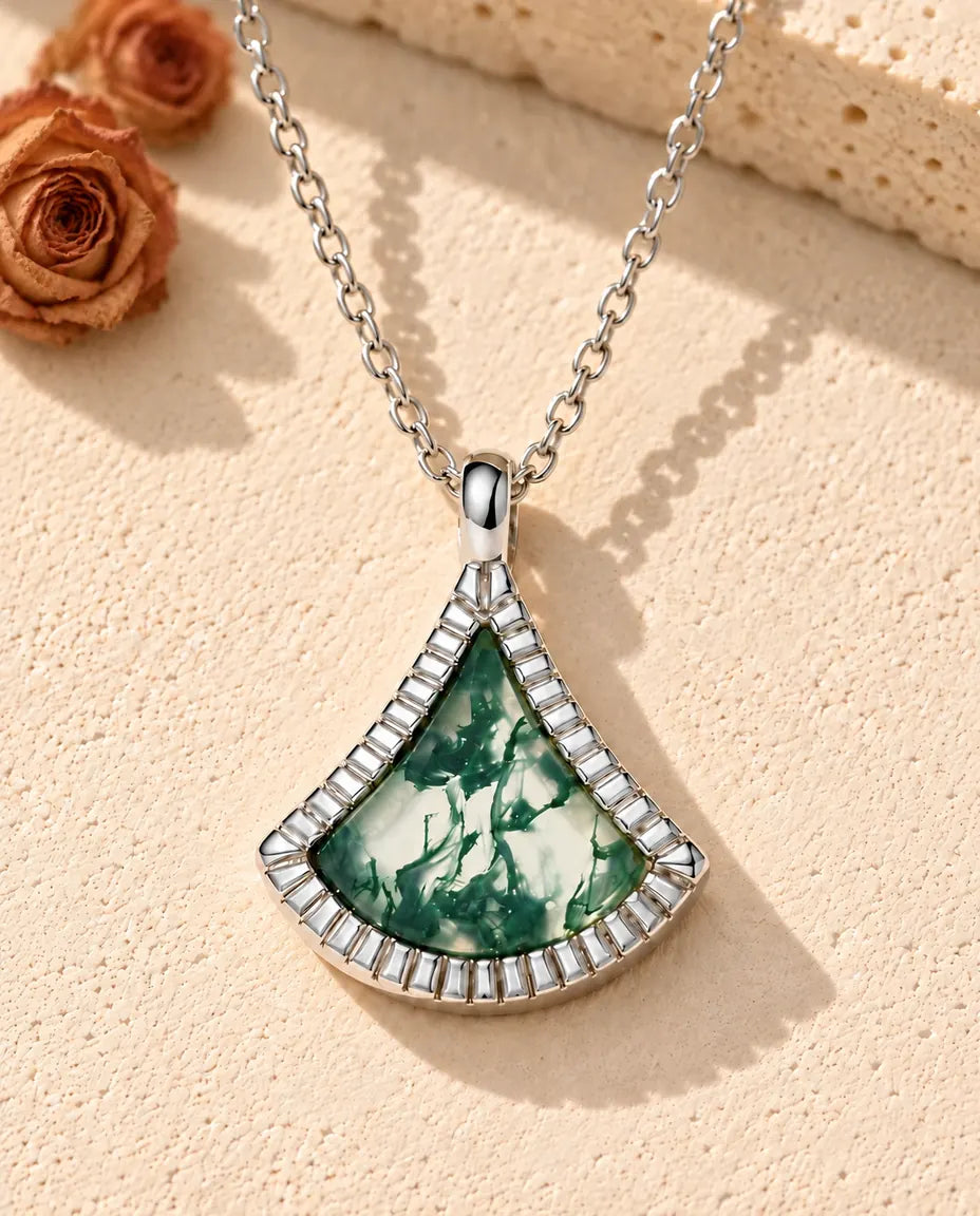 Collar de Ágata Musgosa en Forma de Abanico en Plata 925 - sobre una superficie clara con textura junto a un bloque de travertino
