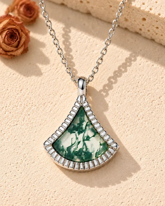 Collar de Ágata Musgosa en Forma de Abanico en Plata 925 - sobre una superficie clara con textura junto a un bloque de travertino
