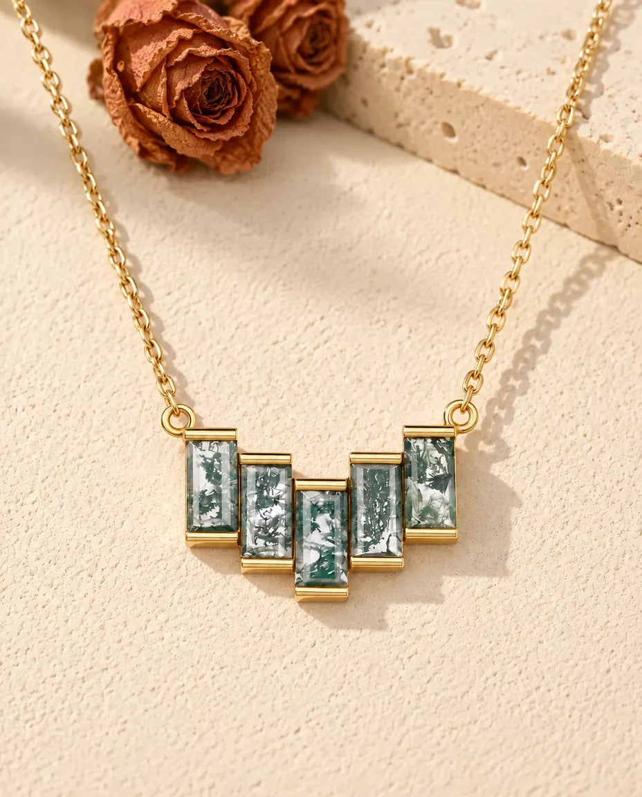 Collar de Ágata Musgosa en Plata 925 Chapada en Oro - sobre una superficie clara con textura junto a un bloque de travertino