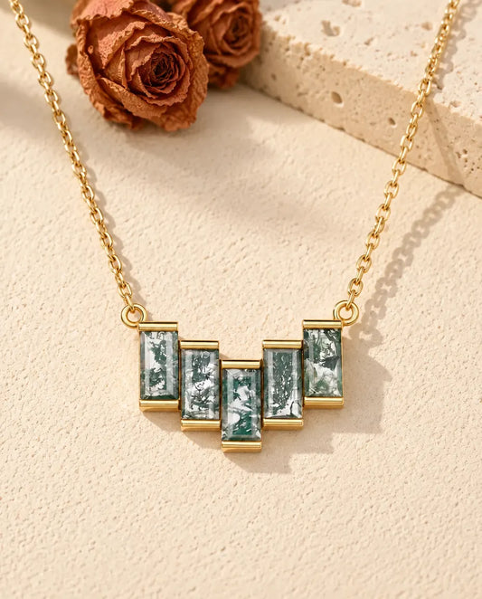 Collar de Ágata Musgosa en Plata 925 Chapada en Oro - sobre una superficie clara con textura junto a un bloque de travertino