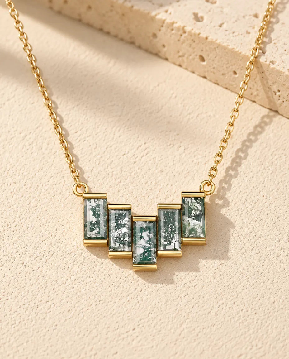 Collar de Ágata Musgosa en Plata 925 Chapada en Oro - sobre una superficie clara con textura junto a un bloque de travertino