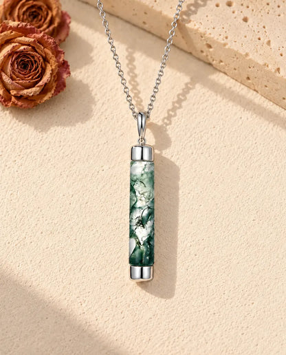 Collar de Ágata Musgosa Cilindro Largo en Plata 925 - sobre una superficie clara con textura junto a un bloque de travertino
