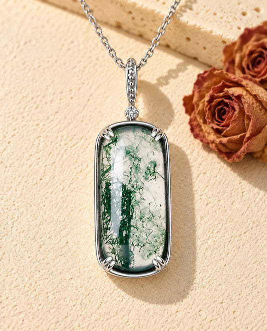 Collar de Ágata Musgosa con Colgante Rectangular en Plata 925 - sobre una superficie clara con textura junto a un bloque de travertino