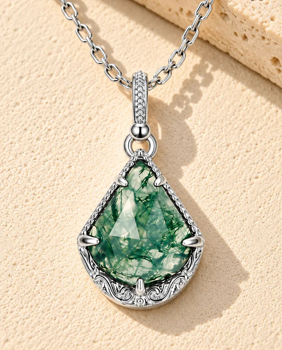 Collar de Ágata Musgosa Escudo en Plata 925 - sobre una superficie clara con textura junto a un bloque de travertino