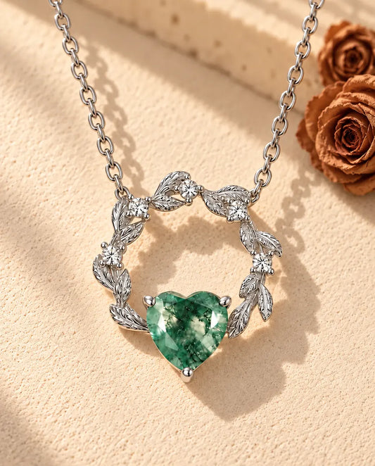 Collar de Corazón de Ágata Musgosa en Plata 925 - sobre una superficie clara con textura junto a un bloque de travertino