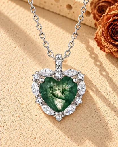 Collar de Ágata Musgosa Corazón con Halo en Plata 925 - sobre una superficie clara con textura junto a un bloque de travertino