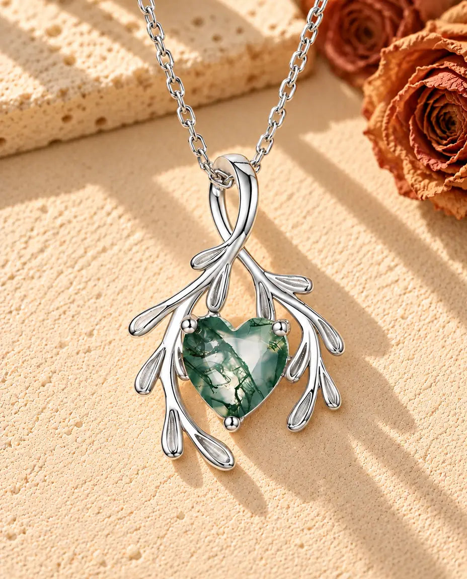 Collar de Ágata Musgosa Corazón y Ramas en Plata 925 - sobre una superficie clara con textura junto a un bloque de travertino
