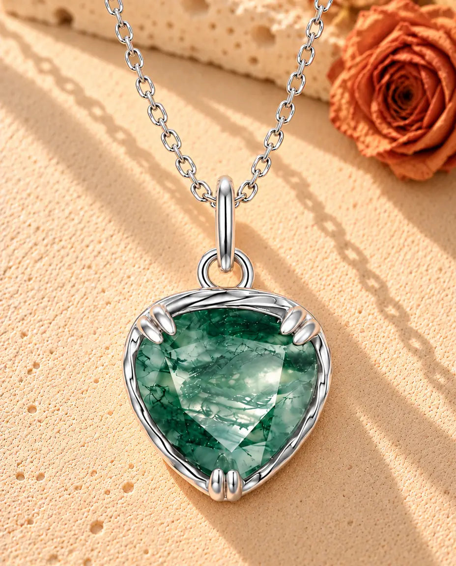 Collar Colgante Corazón de Ágata Musgosa en Plata 925 - sobre una superficie clara con textura junto a un bloque de travertino