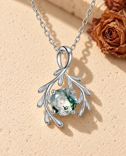 Collar de Ágata Musgosa Rama en Plata 925 - sobre una superficie clara con textura junto a un bloque de travertino