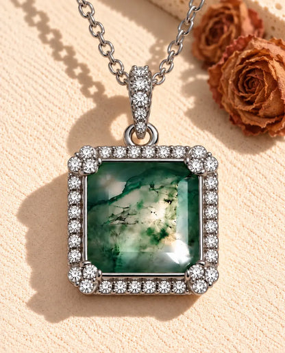 Collar de Ágata Musgosa Cuadrada en Plata 925 - sobre una superficie clara con textura junto a un bloque de travertino