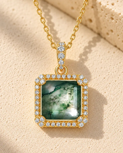 Collar de Ágata Musgosa Cuadrada en Plata 925 - versión dorada sobre una superficie clara con textura junto a un bloque de travertino