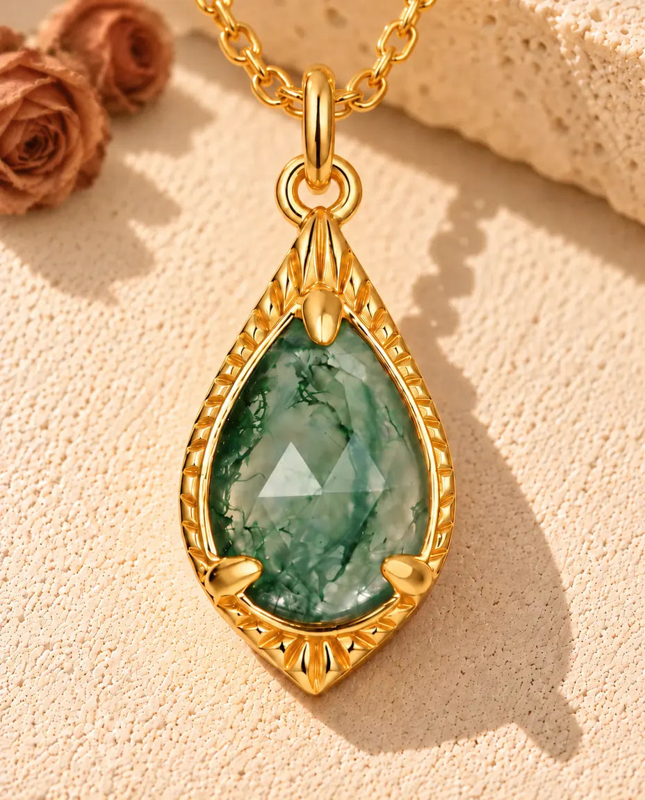 Collar de Ágata Musgosa en Forma de Gota en Plata 925 Chapada en Oro - sobre una superficie clara con textura junto a un bloque de travertino