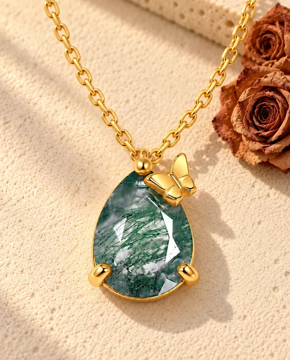 Collar de Ágata Musgosa en Forma de Gota en Plata 925 Chapada en Oro - sobre una superficie clara con textura junto a un bloque de travertino