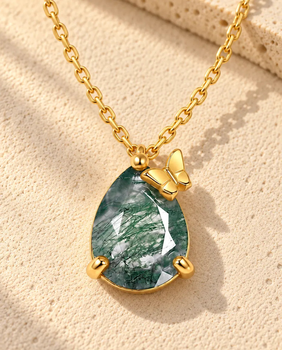Collar de Ágata Musgosa en Forma de Gota en Plata 925 Chapada en Oro - sobre una superficie clara con textura junto a un bloque de travertino